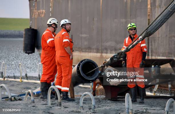 June 2019, Schleswig-Holstein, Büsum: The end of a 516 kilometre long submarine cable is pulled ashore by a cable-laying ship in the mud flats under...