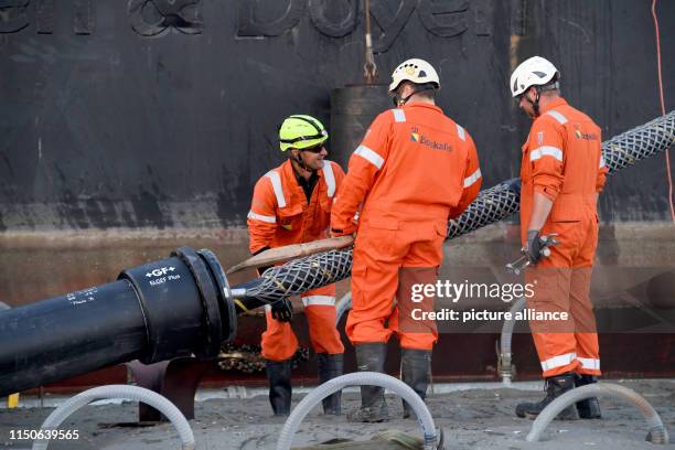 June 2019, Schleswig-Holstein, Büsum: The end of a 516 kilometre long submarine cable is pulled ashore by a cable-laying ship in the mud flats under...