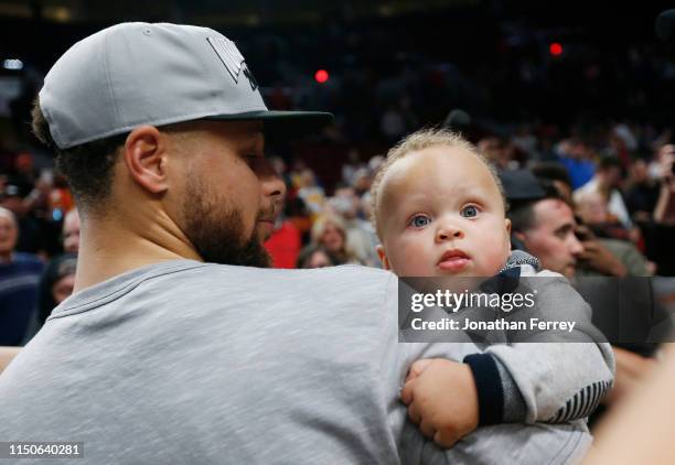 Stephen Curry of the Golden State Warriors holds his son Canon W. Jack Curry after defeating the Portland Trail Blazers 119-117 during overtime in...