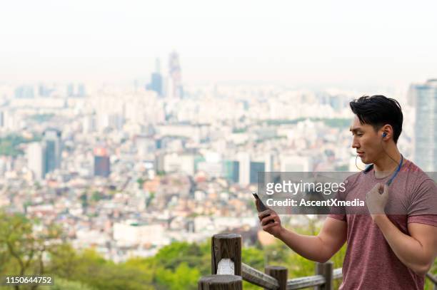 homme d’ajustement écoutant la musique sur des écouteurs dans la ville - seoul stock photos et images de collection