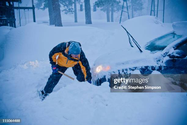 man digging his car out from snow - graven stockfoto's en -beelden