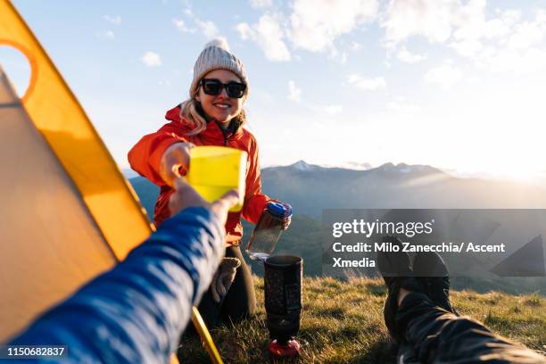 pov of woman handing beverage to camera, view of valley at sunset next to tent - blue cup stock pictures, royalty-free photos & images