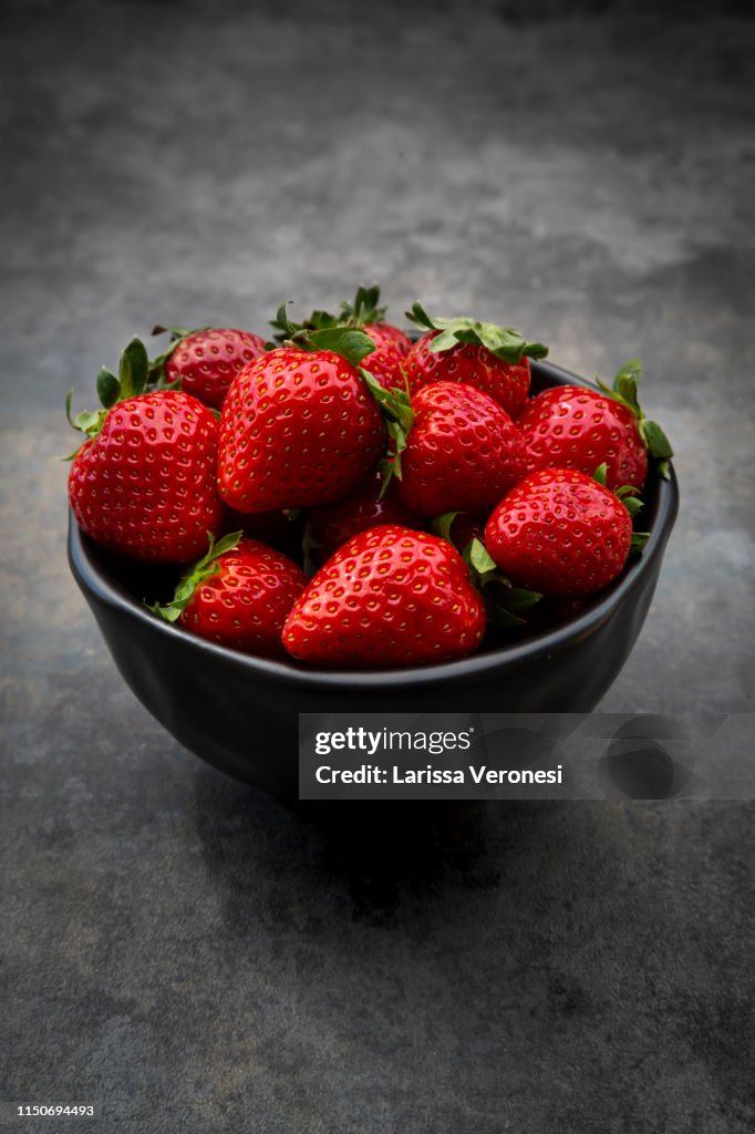 Bowl of strawberries on dark concrete