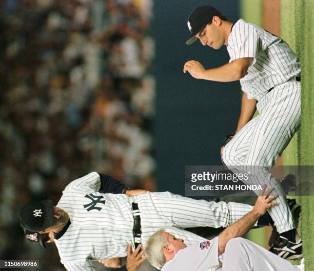 New York Yankee pitcher Andy Pettitte lays on infield as he is tended to by trainer Steve Donohue as manager Joe Torre watches in fifth inning of...