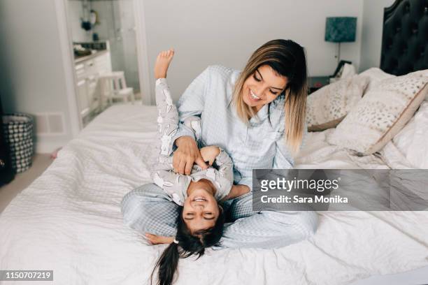 girl being tickled by her mother on bed in morning - kietelen stockfoto's en -beelden