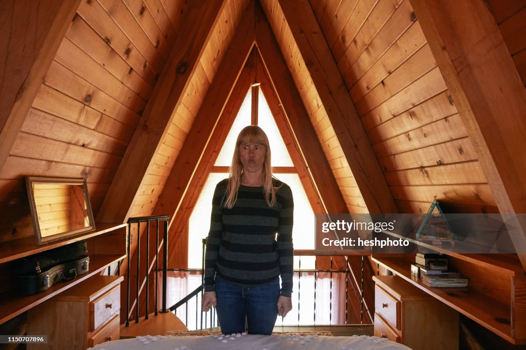 Woman making face in bedroom in A-frame house