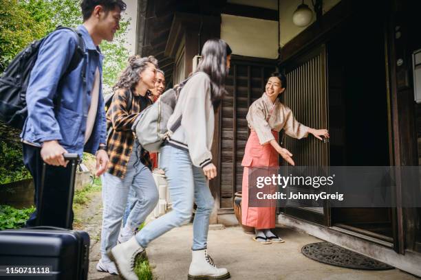 group of young travellers arriving at traditional japanese ryokan inn - social grace stock pictures, royalty-free photos & images