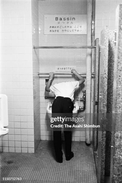 Man vomits at a toilet of the beer garden of the New Tokyo on August 3, 1962 in Tokyo, Japan.