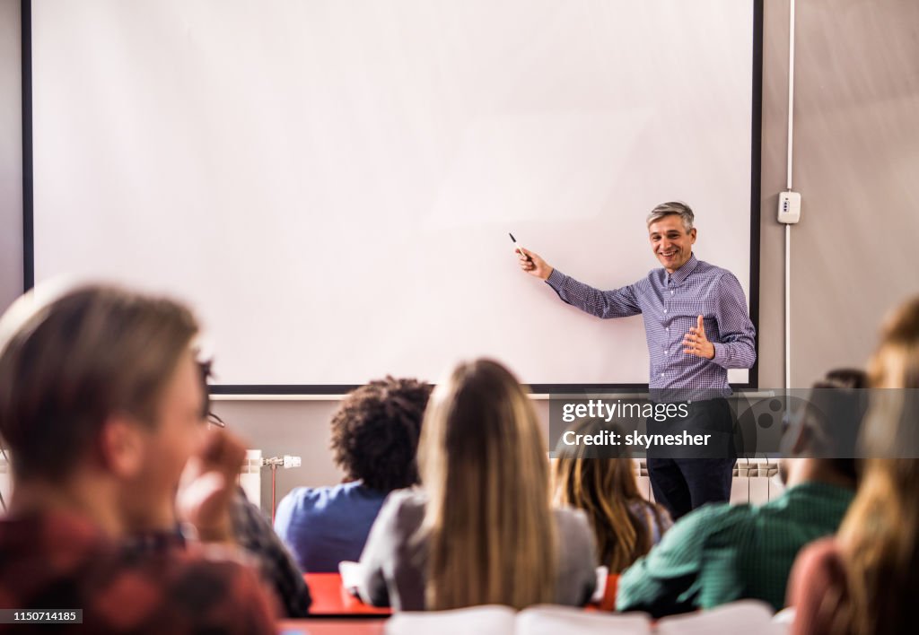 Happy professor teaching a lecture on visual screen in the classroom.