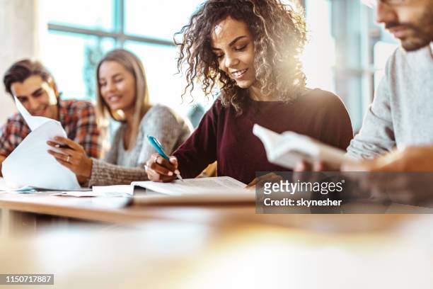 happy female college student reading a book on a class. - education building stock pictures, royalty-free photos & images