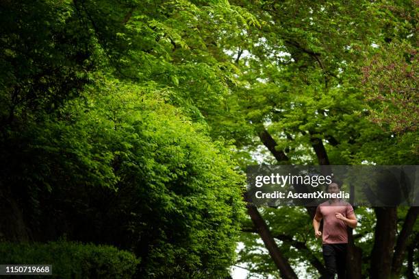 fit mid adult man jogging in forest - surround yourself stock pictures, royalty-free photos & images