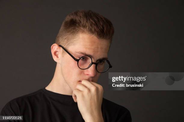 studio portrait of an 18 year old man in a black t-shirt and glasses on a black background - crying man stock pictures, royalty-free photos & images