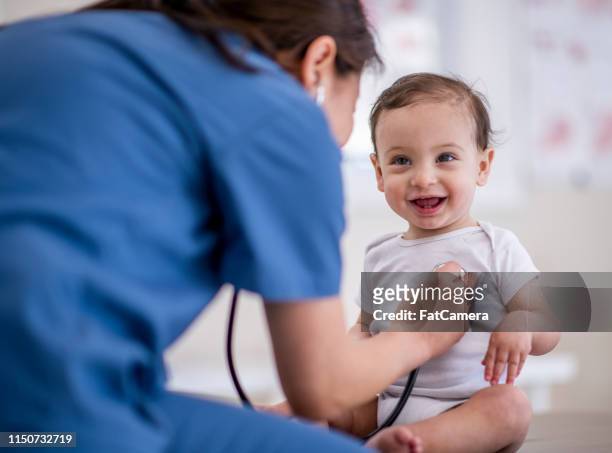 arts geeft baby een checkup - doctor and baby stockfoto's en -beelden
