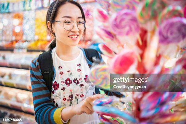 asian girl choosing lollipops in a candy store - chocolatier stock pictures, royalty-free photos & images