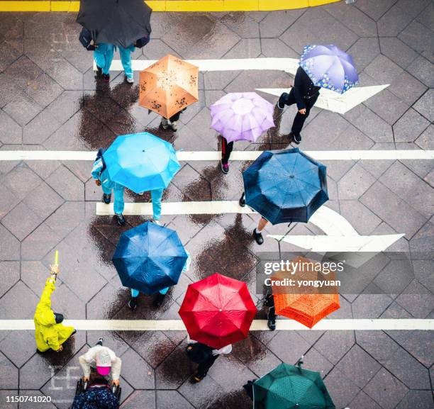 aerial view of walking people using colorful umbrellas in rain - asia rain stock pictures, royalty-free photos & images