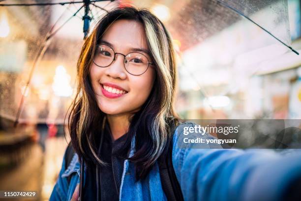 chica asiática tomando un selfie en la lluvia - chinese people posing for camera fotografías e imágenes de stock