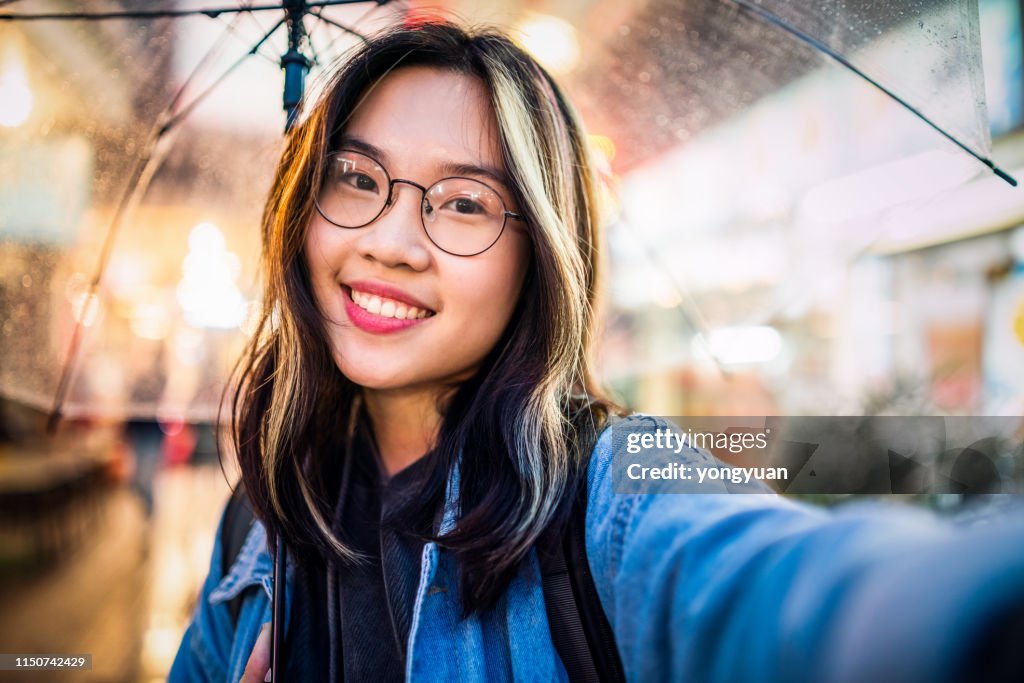 Asian girl taking a selfie in rain