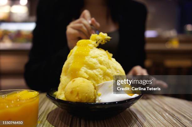 woman eating mango shaved ice dessert - mango shaved ice stock pictures, royalty-free photos & images