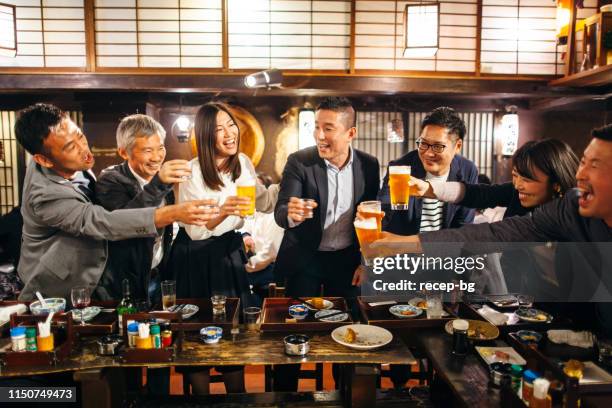 gruppe von japanern, die in der kneipe izakaya im japanischen stil einen feierlichen toast feiern - happy hour stock-fotos und bilder