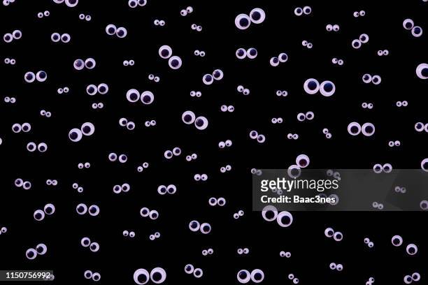 large group og googly eyes on black background - paranoia 個照片及圖片檔