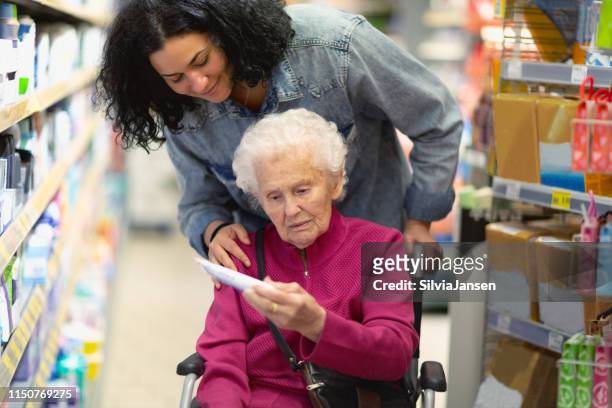 betreuer helfen seniorin beim einkaufen - supermarket help stock-fotos und bilder