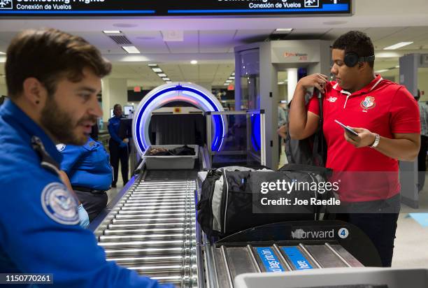 Transportation Security Administration agents help travelers place their bags through the 3-D scanner at the Miami International Airport on May 21,...