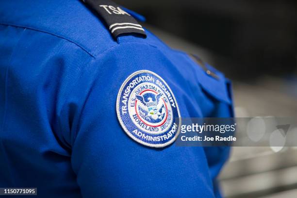 Transportation Security Administration agent's patch is seen as she helps travelers place their bags through the 3-D scanner at the Miami...