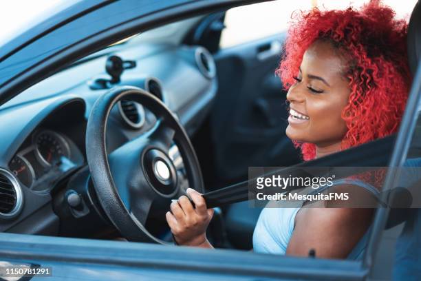 mujer sonriente poniendo el cinturón de seguridad - cinturón azul fotografías e imágenes de stock