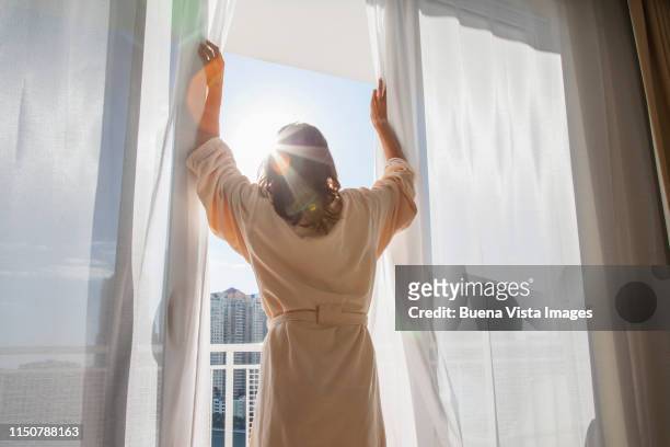 woman opening curtains - open day one stock pictures, royalty-free photos & images