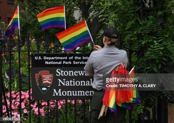 National Park Service ranger places rainbow flags on the fence at the Stonewall National Monument in the West Village neighborhood of Greenwich...