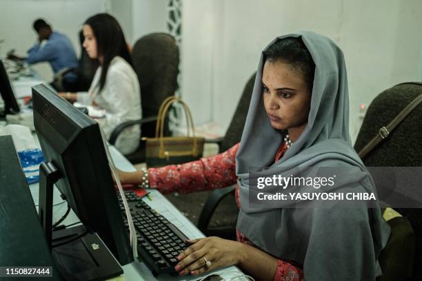 Sudanese woman works at a travel agency in Khartoum on June 17, 2019 as businesses struggle to keep their services going after being hit by an...