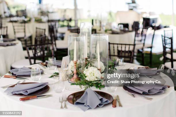 table setting at a tented wedding reception with a mid century modern and frank lloyd wright feel candles, plates, flowers, floral arrangement tables, table number - ricevimento di nozze foto e immagini stock