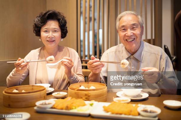 senior chinese couple enjoying steamed buns - dim sum meal stock pictures, royalty-free photos & images