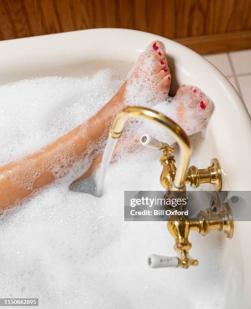 frau nimmt blasenbad mit messinghahn - woman bath bubbles stock-fotos und bilder