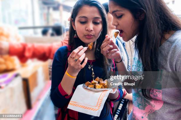 girls eating aloo chaat street food - street food stall stock pictures, royalty-free photos & images