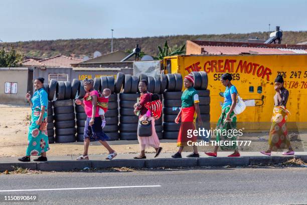 dames africaines vêtues traditionnelles marchant sur le trottoir du canton d’alexandra, johannesburg - alexandra photos et images de collection