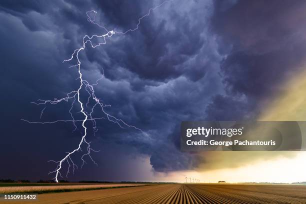 thunder striking over an agricultural field - meteo estremo foto e immagini stock