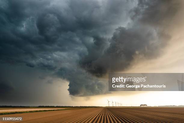 dark clouds over an agricultural field - dark sky stock-fotos und bilder