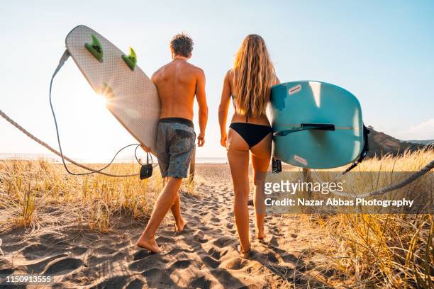 young couple heading out for surfing. - sydney beaches stock-fotos und bilder