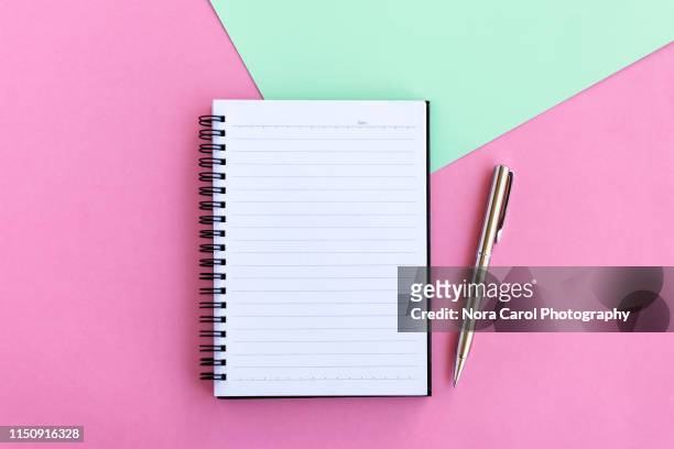 note pad and pen on pink and green background - spiral notebook table stock pictures, royalty-free photos & images