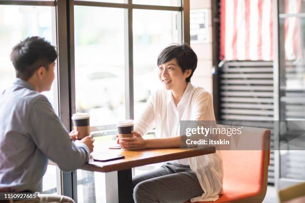 two people enjoy a conversation in a coffee shop. - taipei tea stock pictures, royalty-free photos & images