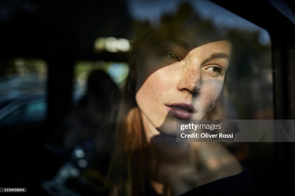 Pensive young woman looking out of car window