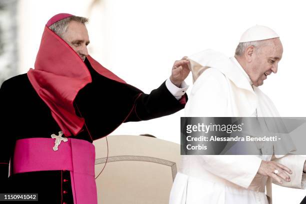 Georg Ganswein, Prefect of the Papal household adjustes Pope Francis mantel during his general weekly audience in St. Peter's Square, on May 22, 2019...