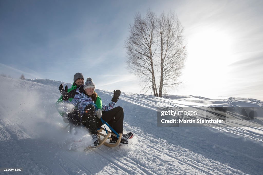 Junges Mädchen auf Schlitten rodelt im Schnee
