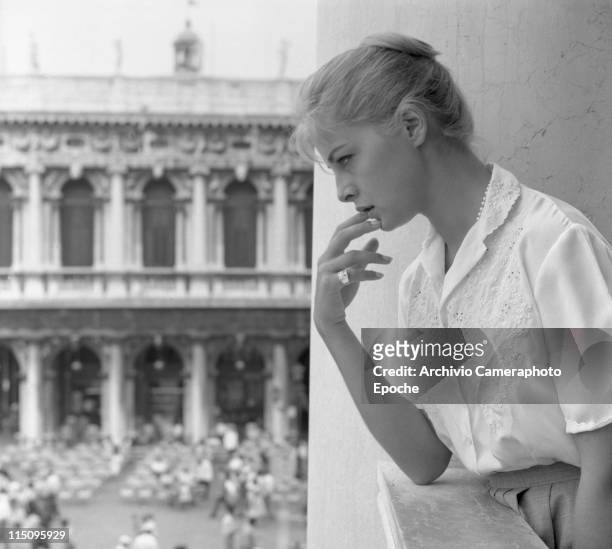 Italian actress Virna Lisi, looking out the balcony of Palazzo Ducale, in St. Mark Square, wearing an embroidered white shirt and a skirt, her hair...