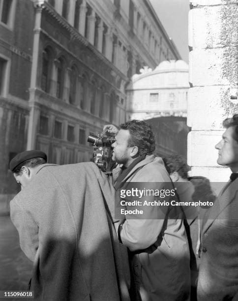 American film director Orson Welles, shooting with a cinecamera on the set of the movie Othello, filming next to the Ponte dei Sospiri, members of...
