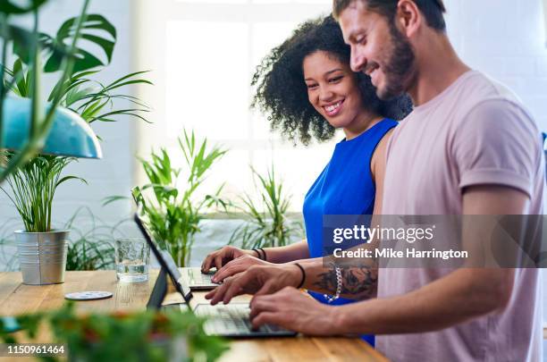 young creative team working in contemporary sustainable office environment - two people side by side stock pictures, royalty-free photos & images