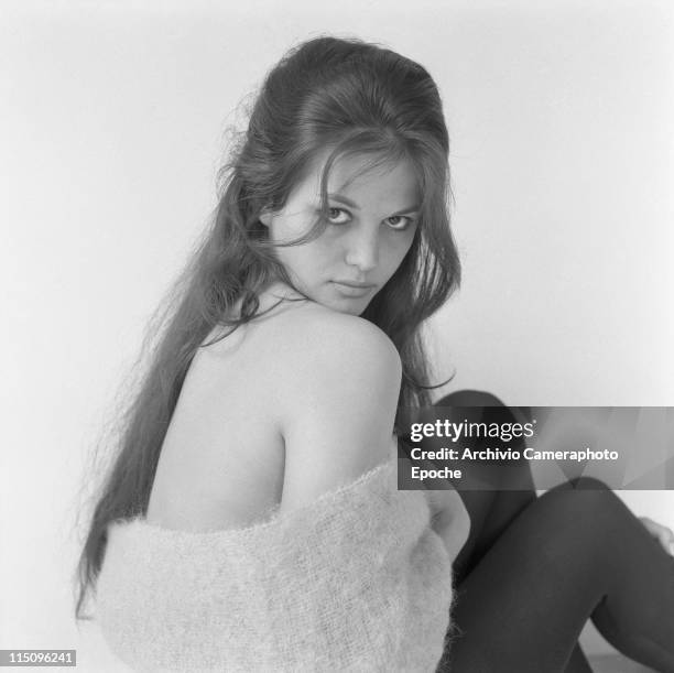 Italian actress Claudia Cardinale, looking behind her right shoulder, wearing a woolen scarf and black tights, Rome 1959.