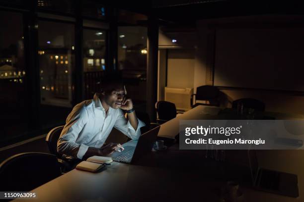 tired young businessman in office at night typing on laptop - working overtime stock pictures, royalty-free photos & images