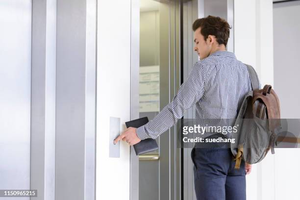 businessman pressing button to open elevator doors - elevator doors stock pictures, royalty-free photos & images